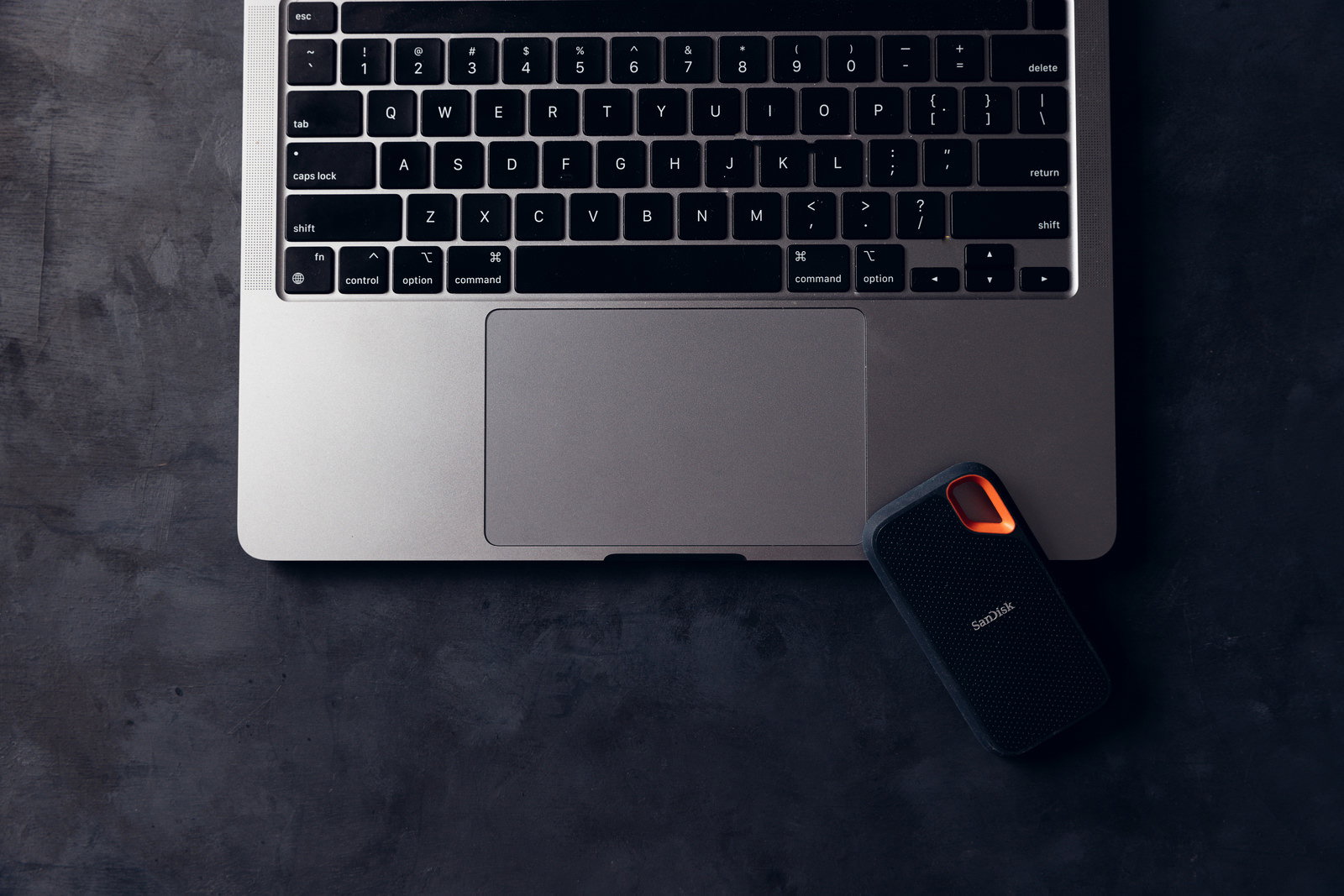 MacBookの横に置かれた黒い外付けストレージデバイス