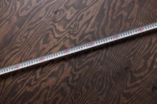 木目模様の板にかけた白いメジャー巻き尺で計測
