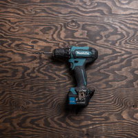 ドライバドリルの鼓動 木目板の上に置かれたハンディマンの詩の写真