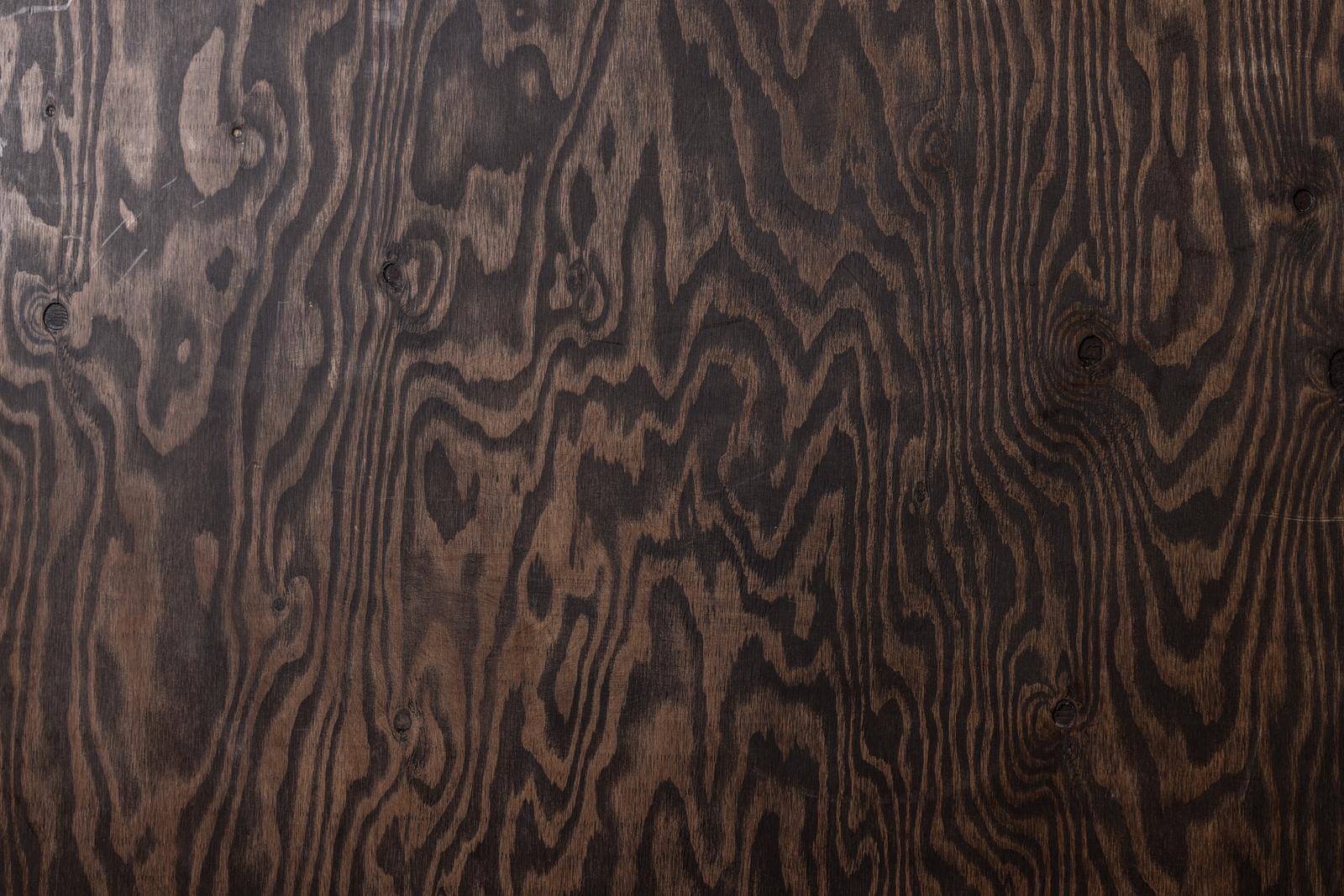 A dark brown wooden board with visible annual rings and knots in the wood grain texture
