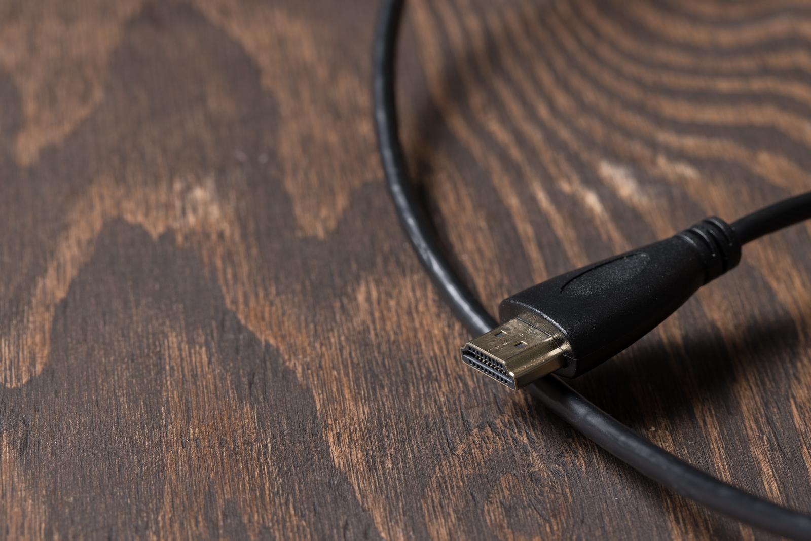 木製テーブルの上に置かれた黒いHDMIケーブルとコネクタ