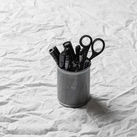 メタルメッシュのペン立てに収納した黒いペンとはさみの写真