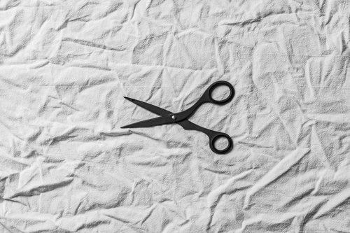 白い布地の上に置かれた黒いハサミ、手芸やクラフト向け