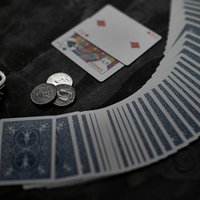 コインを前に扇状に並べたトランプの勝負と黒い布地の机上の写真