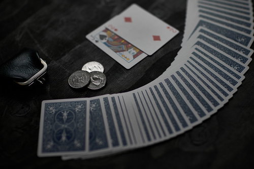 コインを前に扇状に並べたトランプの勝負と黒い布地の机上