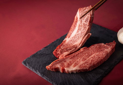 黒いスレートの上で箸でつまむ霜降りサーロインの厚みをチェック