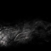 薄く立ち上る白いスモークの流れ 黒背景のモノクロ抽象テクスチャの写真