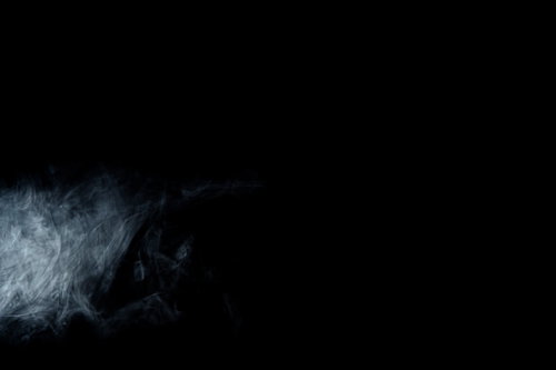 暗闇に立ち上る薄い白い煙のもくもくした流れ
