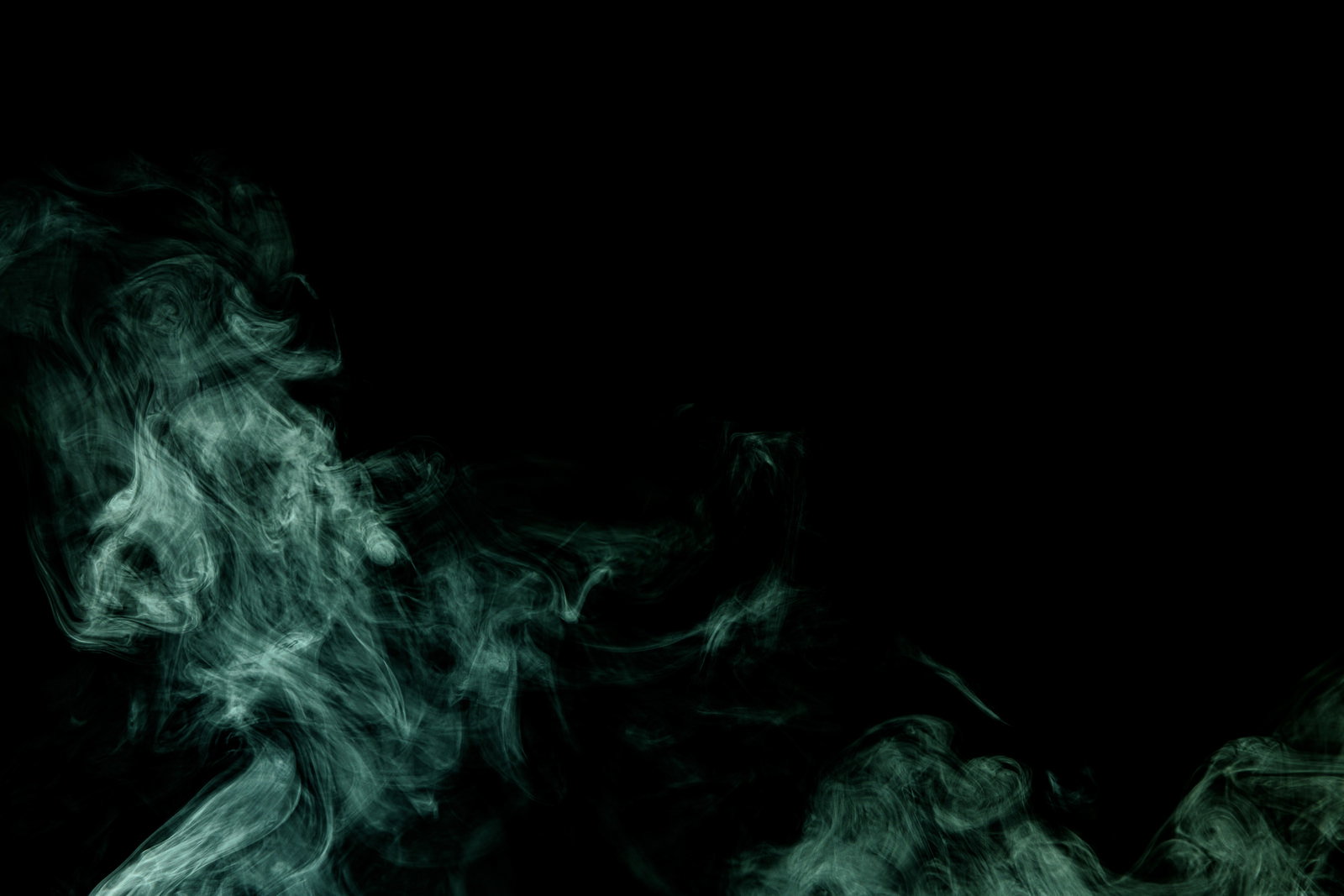 黒い背景に緑色の煙が流れるように広がっている様子