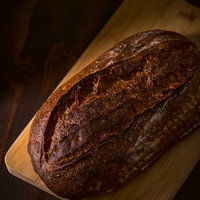 暗がりの木製まな板に置かれた焼きたてパンの写真