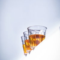 白い背景に縁に並んだグラスに入った琥珀色のお茶の写真