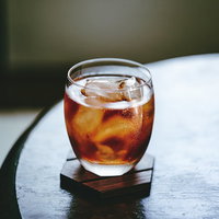 グラスに注がれた冷たい麦茶と氷、木製テーブルの写真