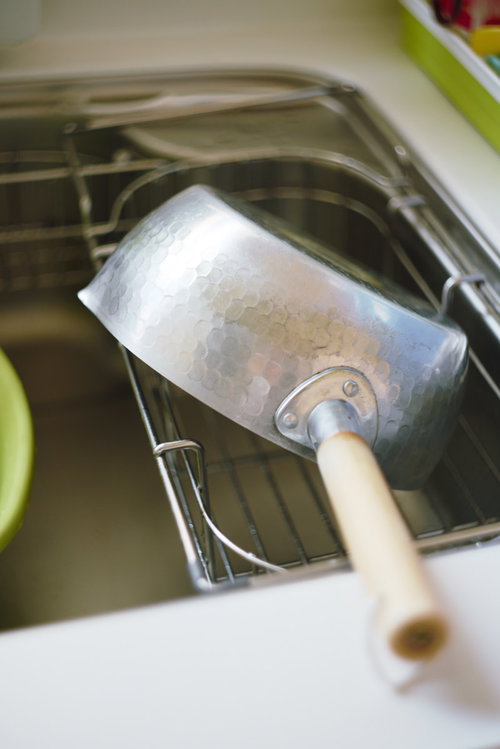 ステンレス製の流しに置かれた白い取っ手の鍋