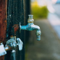 蛇口に張られた蜘蛛の巣と古い水栓金具の風景の写真