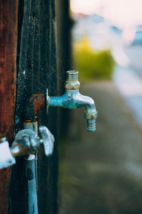 蛇口に張られた蜘蛛の巣と古い水栓金具の風景