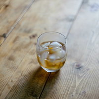 木の床に置かれた冷たい麦茶とグラスの写真