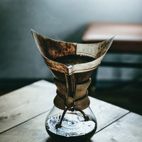 木製テーブルの上でハウスメーカーのコーヒーメーカーでドリップ中の写真