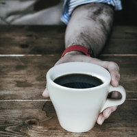 コーヒーカップを掴む手元のカフェシーン、温かい珈琲の一杯の写真