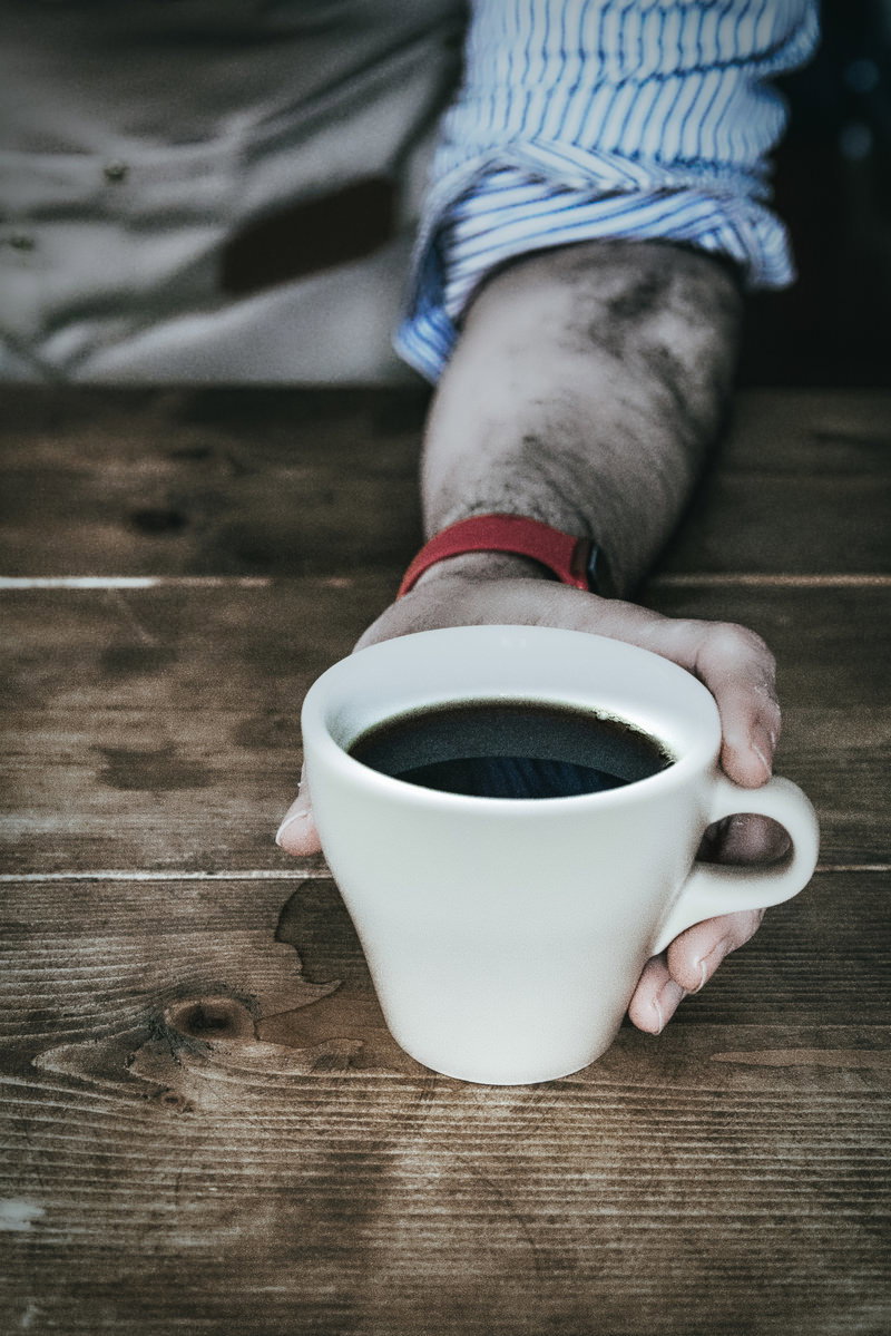 白いコーヒーカップを手で持つ手元のクローズアップ