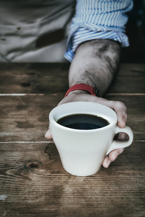 コーヒーカップを掴む手元のカフェシーン、温かい珈琲の一杯