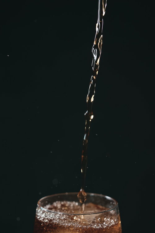 透明なグラスに勢いよく注ぐ琥珀色の麦茶のスプラッシュ