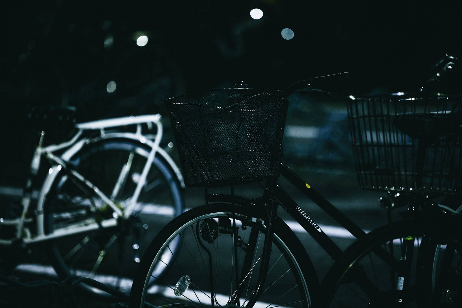 早朝の薄暗い駐輪場に複数の自転車が並んでいる様子