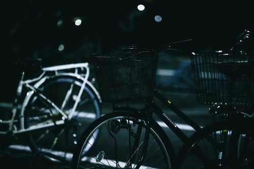 早朝の薄暗い駐輪場に並ぶ自転車と街灯の光