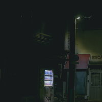 深夜の暗がりに立つ自動販売機の写真
