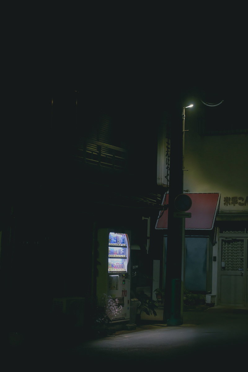 深夜の路地で光る自動販売機