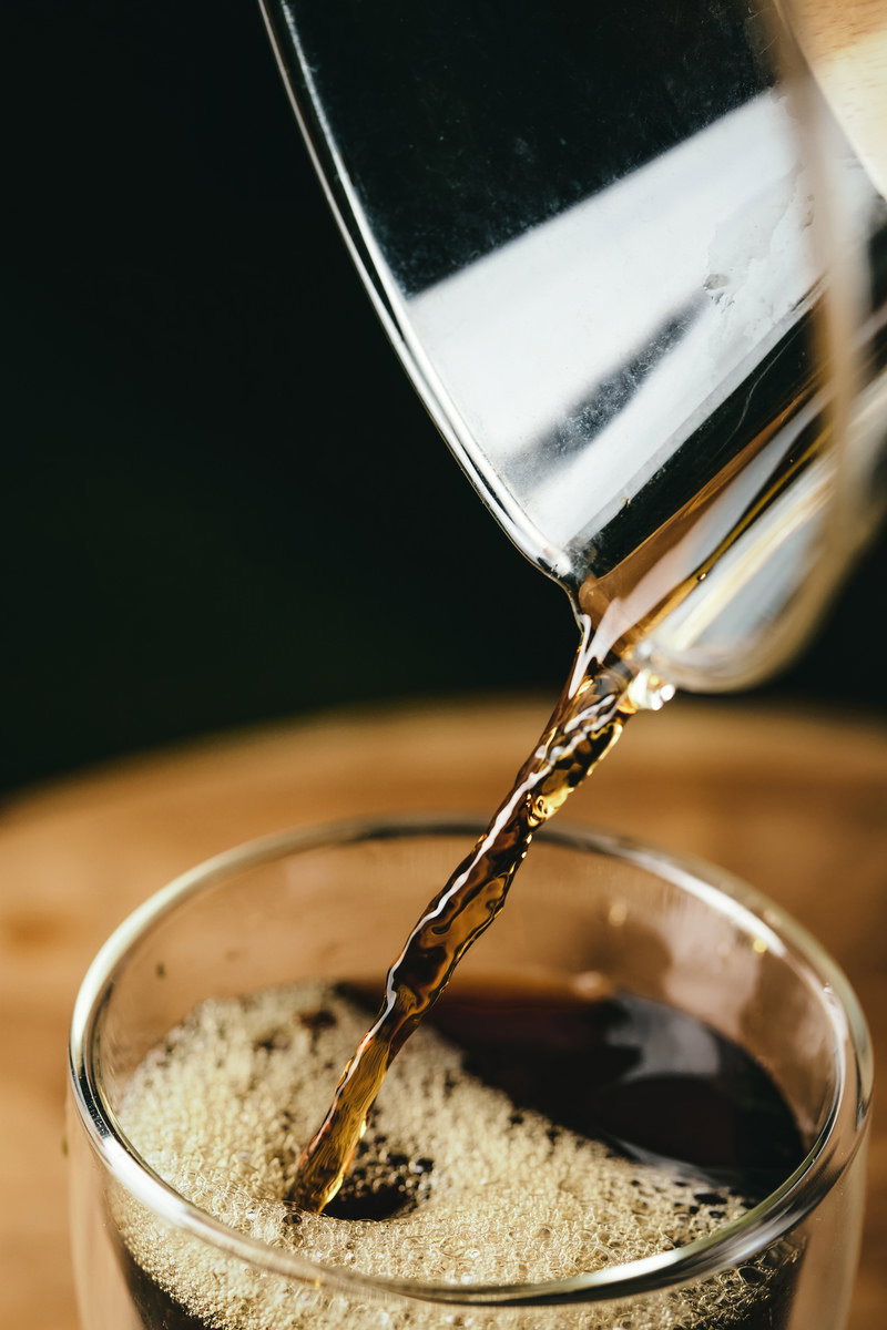 コーヒーメーカーのガラス容器から茶色いコーヒーが注がれている様子
