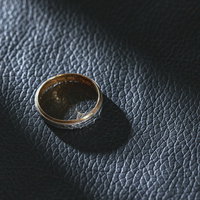 黒いレザーの上に置かれた指輪にあたる光と影の写真