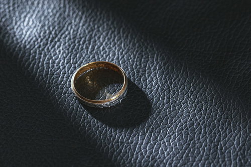 黒いレザーの上に置かれた指輪にあたる光と影