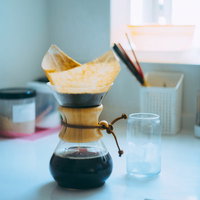 木製フィルターでドリップ中のコーヒーメーカーと空のグラスの写真