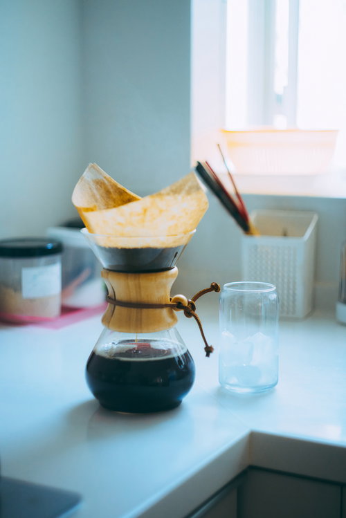 木製フィルターでドリップ中のコーヒーメーカーと空のグラス