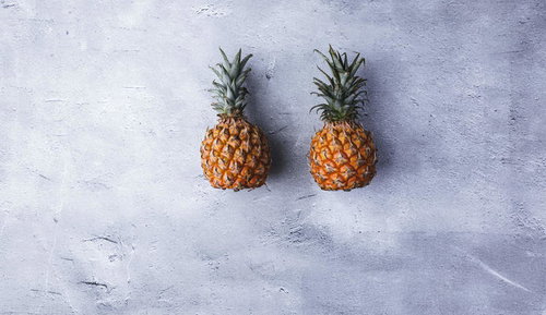 コンクリート上に並べたパイナップル2個の静物