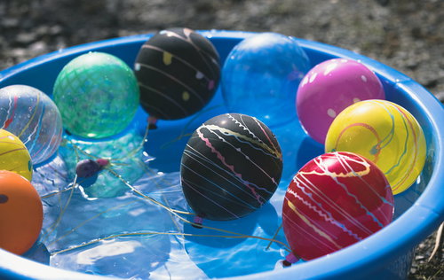 夏祭りの桶に浮かぶカラフルな水風船とヨーヨー