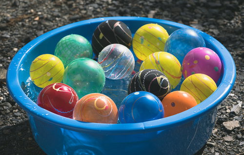 桶に浮かぶカラフルな水風船とヨーヨーの夏祭り