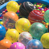 青い容器に浮かぶカラフルなヨーヨーとスーパーボールの写真