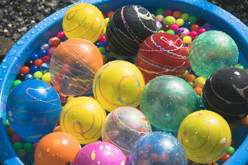 青い容器に浮かぶカラフルなヨーヨーとスーパーボール