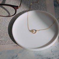 白い皿の上に置かれたゴールドネックレスと眼鏡の写真