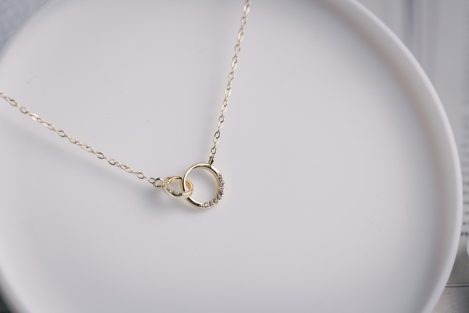 白い皿の上に丁寧に置かれた繊細なゴールドチェーンネックレス