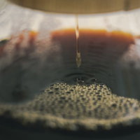 コーヒーの雫が落ちて波紋を作るドリップコーヒーの抽出シーンの写真