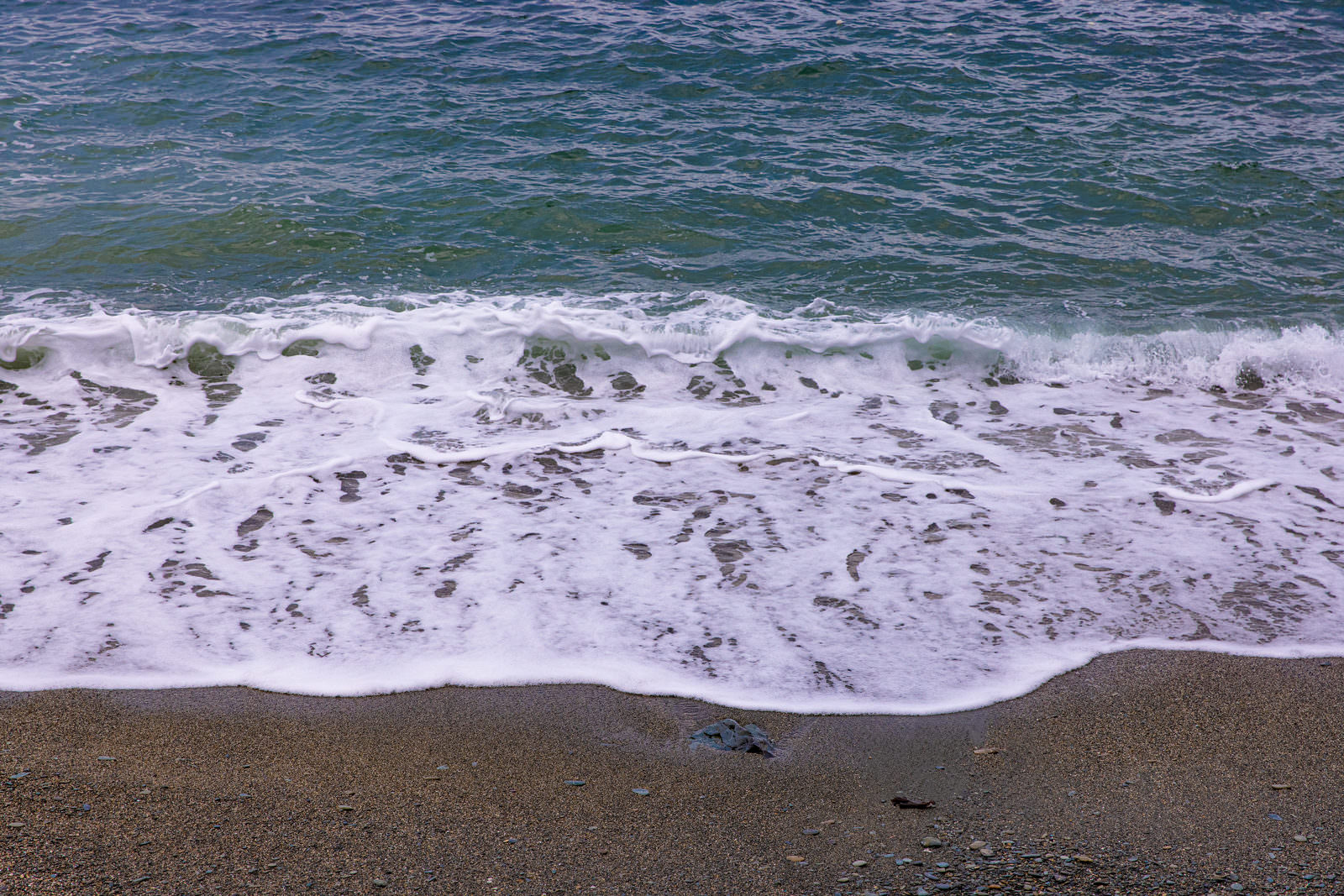 海水浴場の砂浜に白い泡を立てて打ち寄せる波