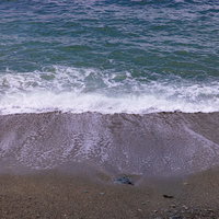 波打ち際の浜辺に打ち寄せる波と砂浜の接点の写真