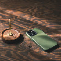 木目のテーブルに置かれた緑色のスマートフォンとお香立ての風景の写真