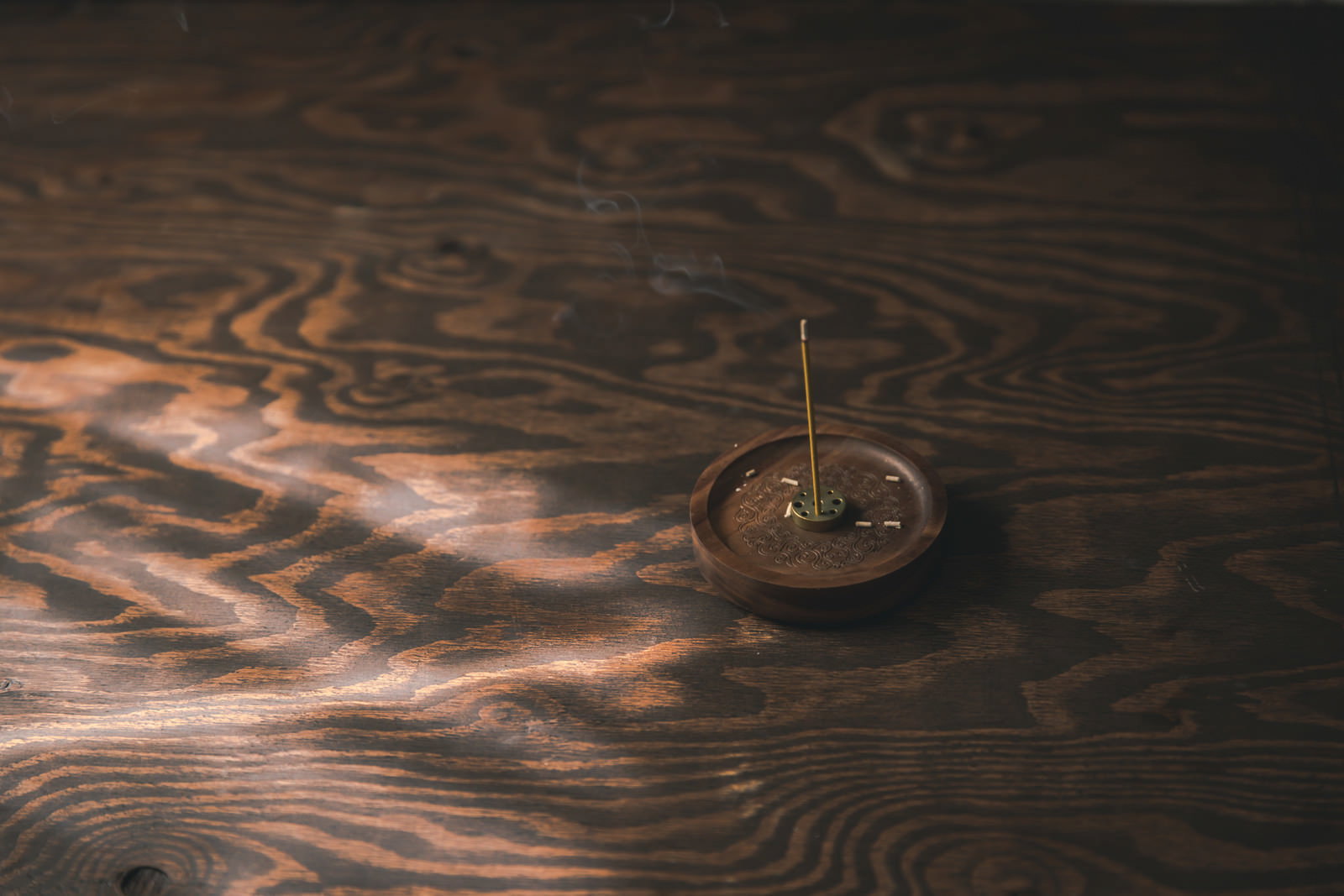 White smoke rising from an incense holder on a wooden desk
