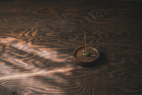 木目の机に置かれたお香立てから立ち上る煙