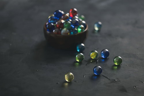 木製の器から零れ落ちたカラフルなビー玉と球体