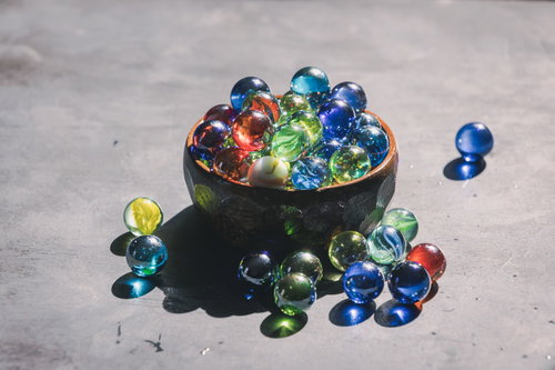 木製の器に集められたカラフルなビー玉の詰め合わせ