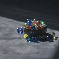 光が当たるビー玉と木の小鉢の写真